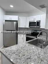 a kitchen with granite countertop a refrigerator and a sink