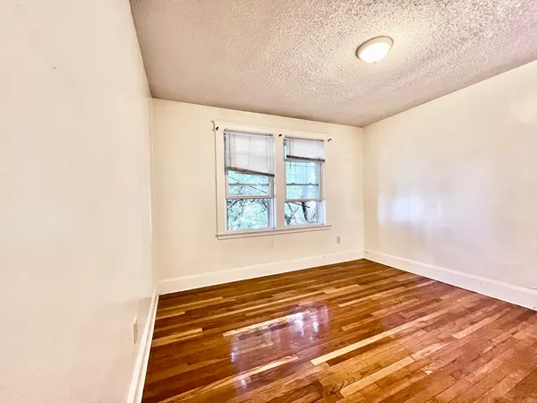 a view of empty room with window and wooden floor