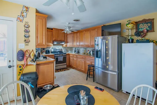 a kitchen with stainless steel appliances granite countertop a refrigerator a stove top oven a sink and a dining table