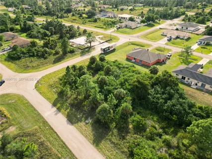an aerial view of residential houses with outdoor space and trees all around