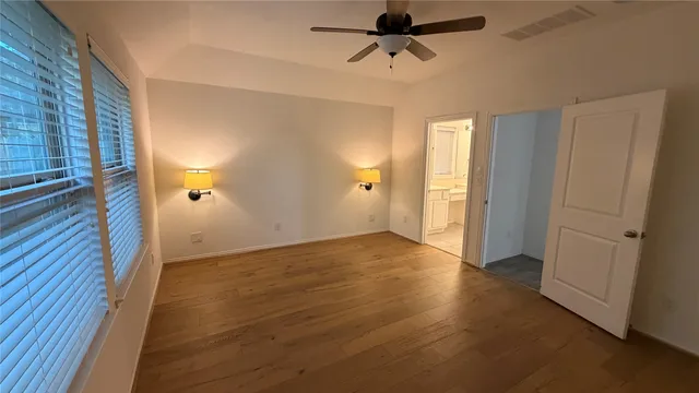 a view of empty room with wooden floor and fan