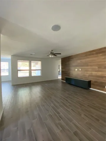 a large white kitchen with granite countertop a stove a sink a refrigerator and white cabinets with wooden floor