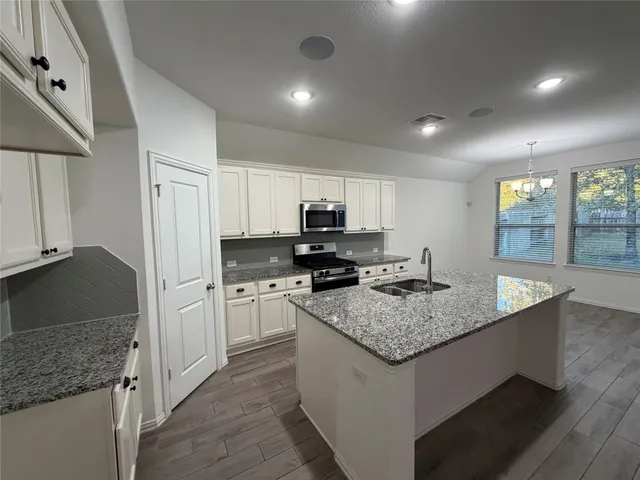 a kitchen with granite countertop a sink stove and cabinets