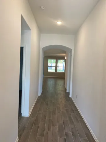 a view of a hallway with wooden floor and a living room