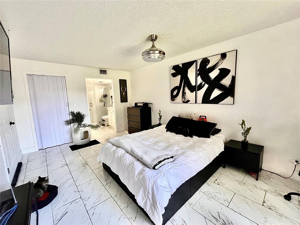 8301 Sands Point Boulevard, Unit 306S Tamarac, FL 33321 - Photo 3 of 10 a bedroom with a bed and wall painting