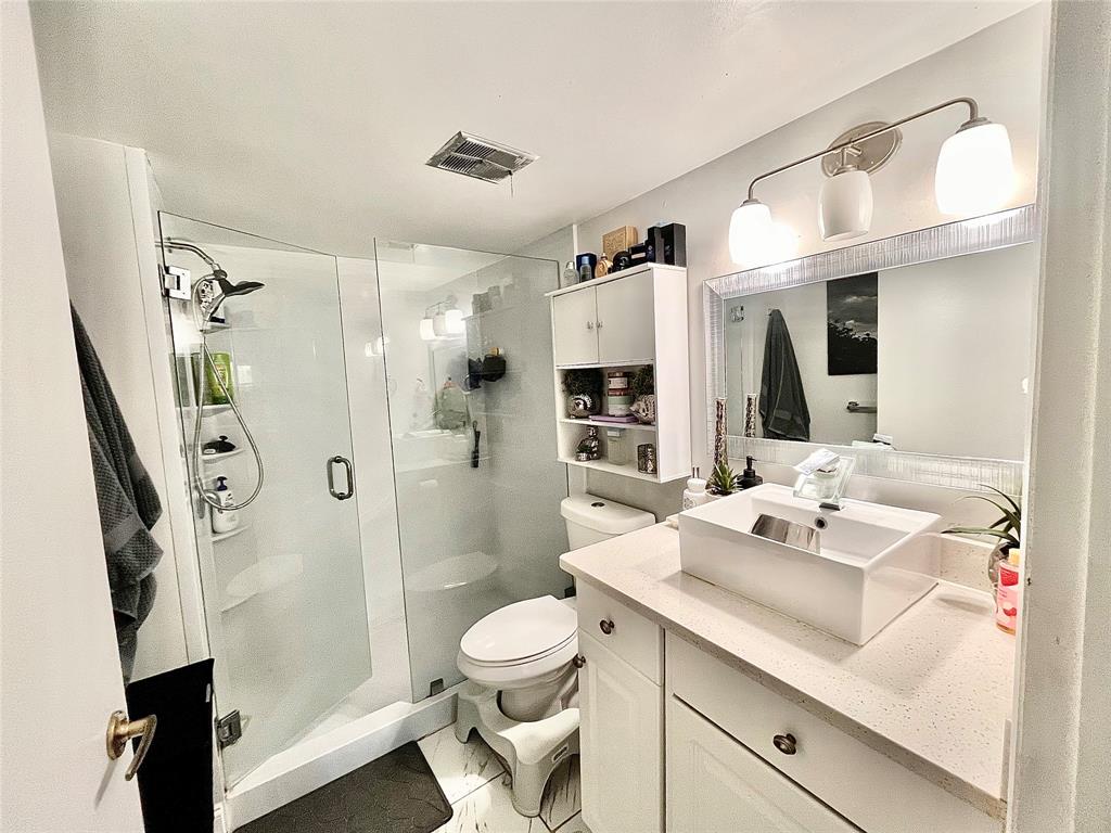 8301 Sands Point Boulevard, Unit 306S Tamarac, FL 33321 - Photo 4 of 10 a bathroom with a sink a toilet a mirror and shower