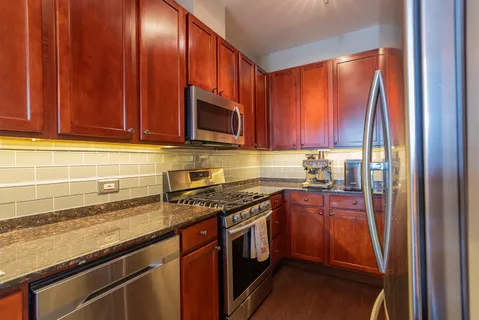 a kitchen with stainless steel appliances granite countertop wooden cabinets a stove top oven a sink and dishwasher