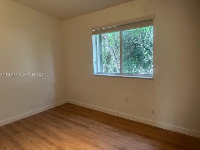 a view of a room that has wooden floor and window