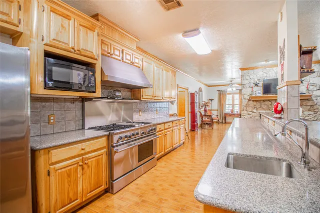 a view of a kitchen with kitchen island granite countertop a large counter top and a stove