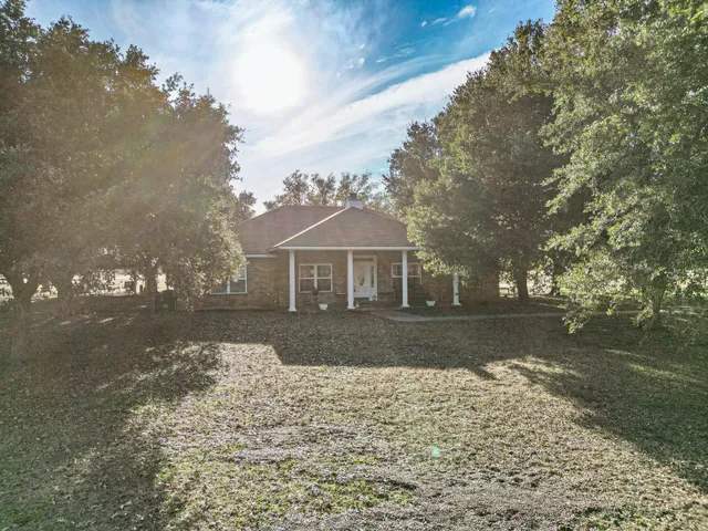a front view of a house with a garden and trees