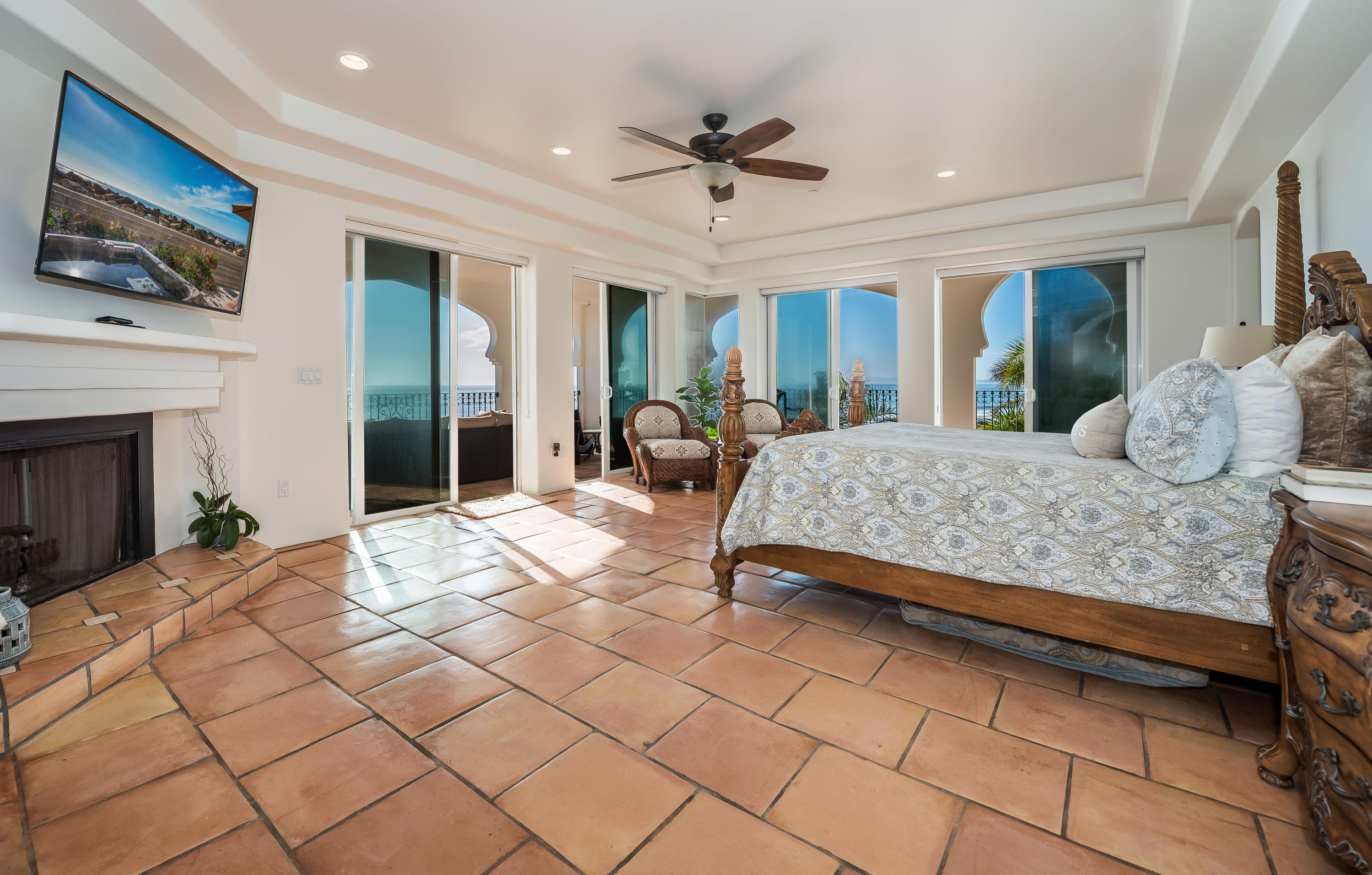 875 Sand Point Road Carpinteria, CA 93013 - Photo 10 of 25 a bedroom with a large bed a flat screen tv and a fireplace