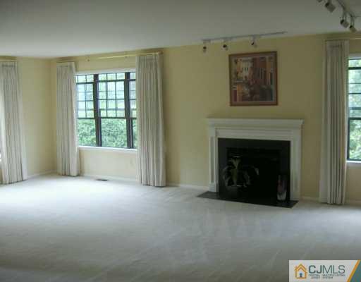 4701 Stonehedge Road Edison, NJ 08820 - Photo 3 of 8 a view of an empty room with a fireplace and a window