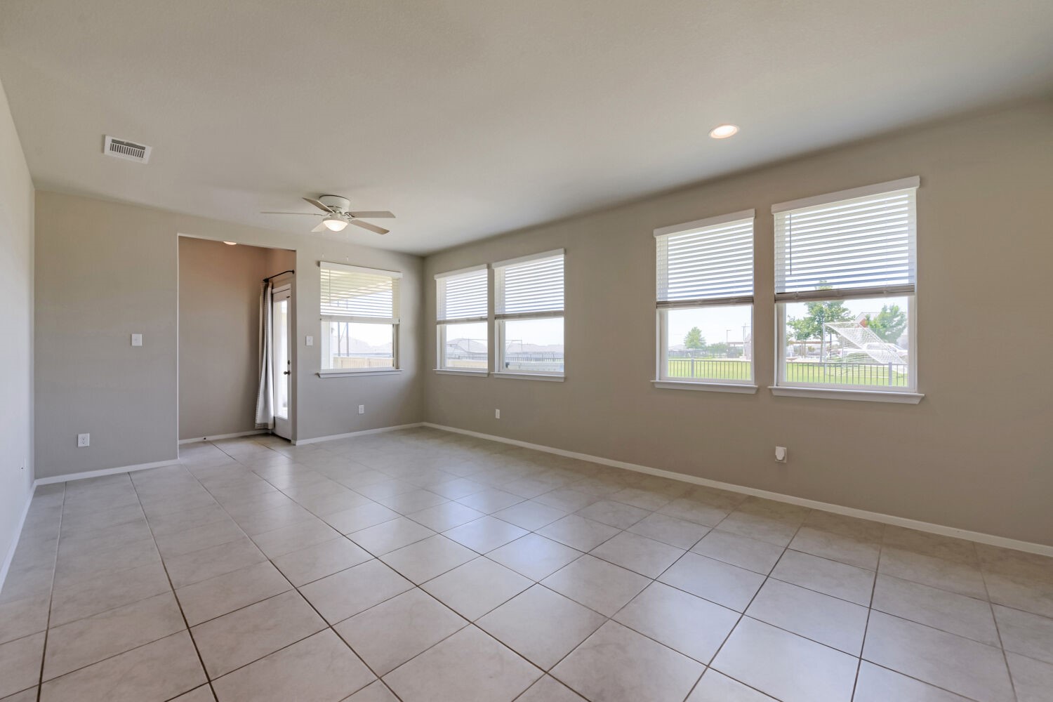 1310 Goforth Road Kyle, TX 78640 - Photo 8 of 24 Spacious room featuring neutral-toned tile flooring, light grey wall paint, and multiple windows with blinds