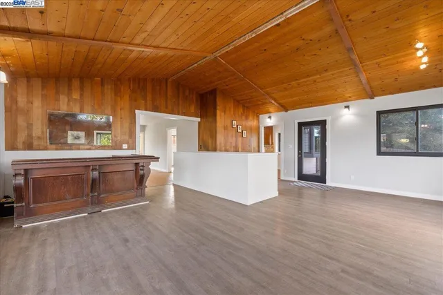 a view of an empty room with a fireplace and wooden floor