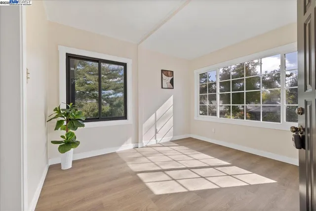a view of an empty room with wooden floor and a window