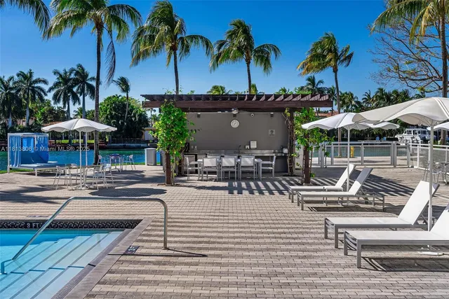 a view of a patio with a table and chairs under an umbrella with palm trees