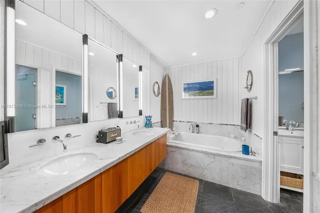 a bathroom with a sink double vanity granite tub shower and a mirror