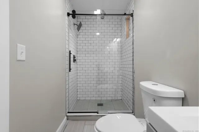 a white toilet sitting next to a shower