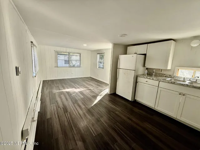 a kitchen with a refrigerator and white cabinets