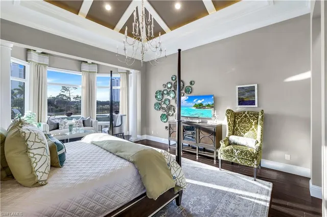 a bedroom with a bed a chandelier and table