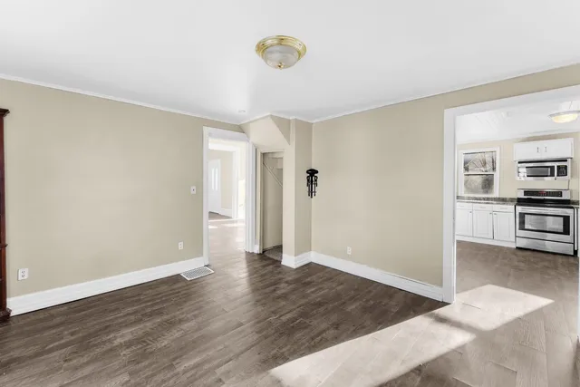 a view of an empty room with kitchen and window
