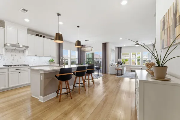 a kitchen with a table chairs stove and white cabinets