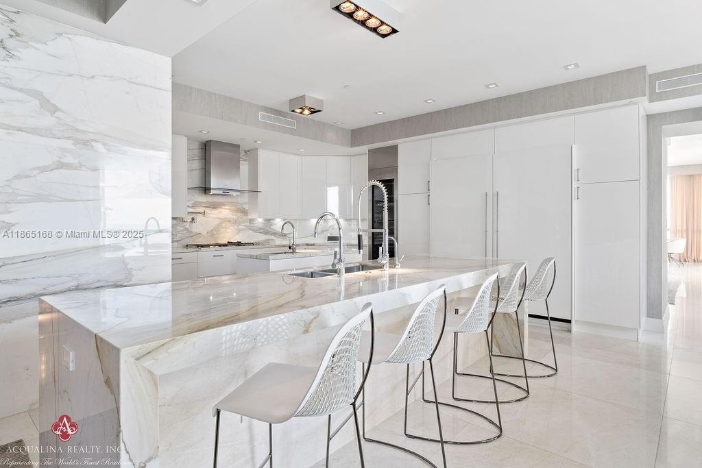 17749 Collins Avenue, Unit 902 Sunny Isles Beach, FL 33160 - Photo 24 of 82 a kitchen with kitchen island granite countertop a table and chairs