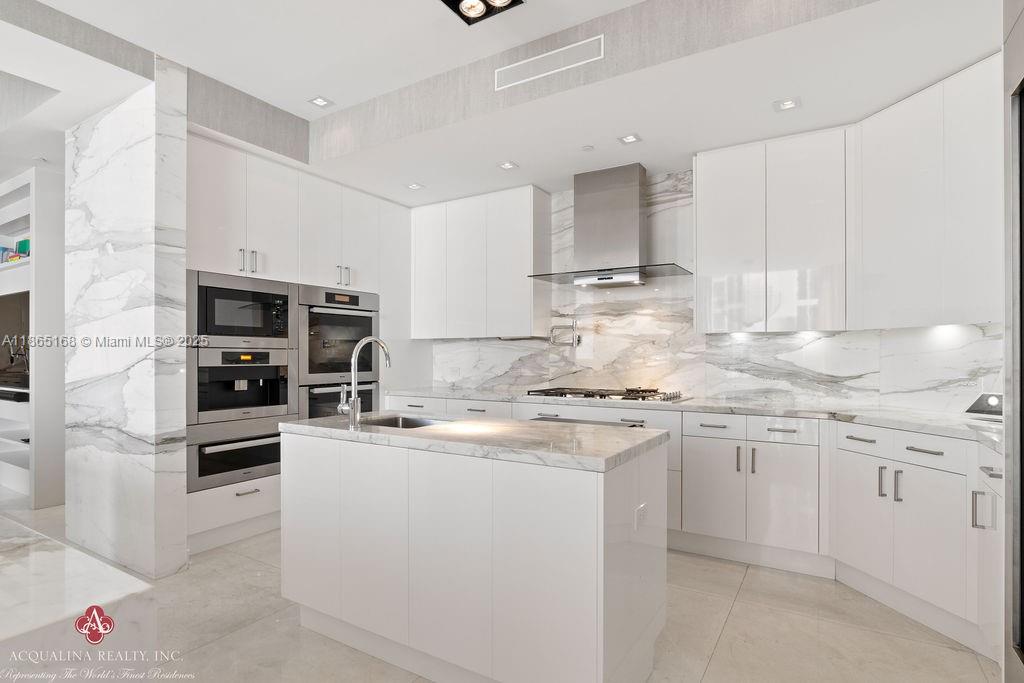 17749 Collins Avenue, Unit 902 Sunny Isles Beach, FL 33160 - Photo 26 of 82 a kitchen with stainless steel appliances granite countertop a sink stove oven and white cabinets