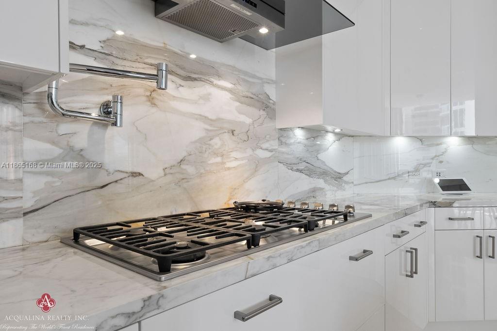 17749 Collins Avenue, Unit 902 Sunny Isles Beach, FL 33160 - Photo 30 of 82 a stove sitting inside of a kitchen with white cabinets