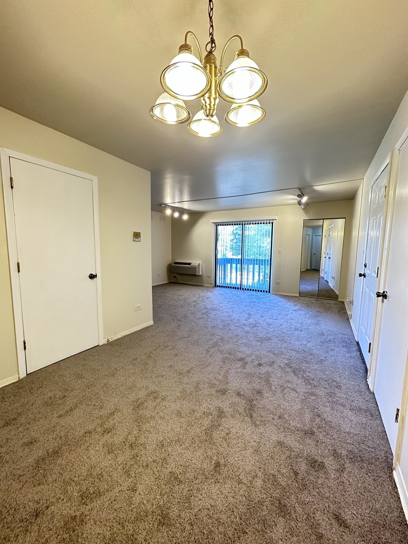 270 12th Street, Unit 2D Wheeling, IL 60090 - Photo 7 of 12 an empty room with a mirror and a chandelier