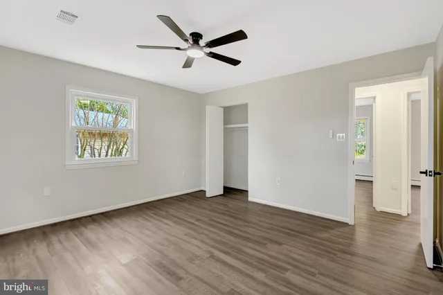 a view of an empty room with wooden floor and closet