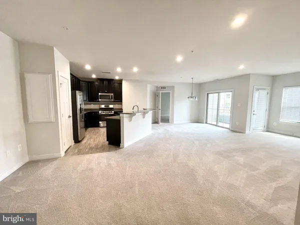 a view of a kitchen with kitchen island a sink stainless steel appliances and cabinets
