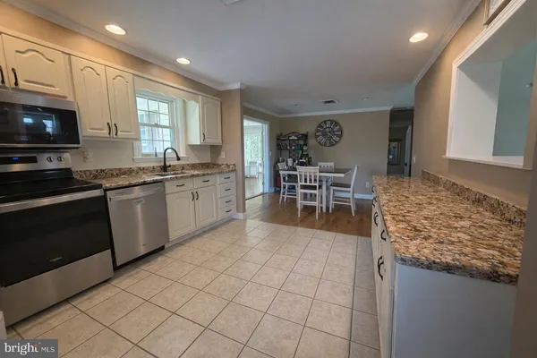 a kitchen with stainless steel appliances granite countertop a stove top oven a sink dishwasher a dining table and chairs with wooden floor
