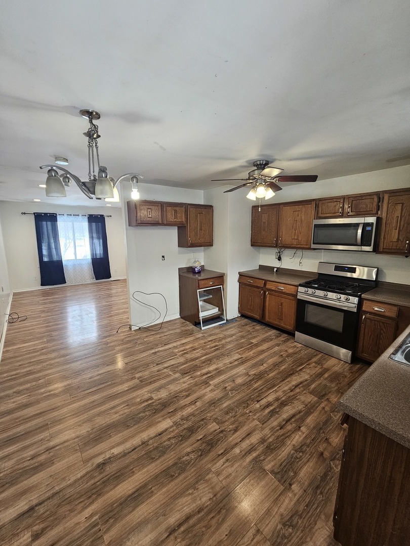 522 Manor Place Aurora, IL 60506 - Photo 4 of 16 a kitchen with stainless steel appliances wooden floor and chandelier