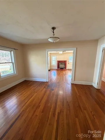 an empty room with wooden floor ceiling fan and windows