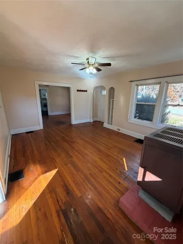 a view of an empty room with window and wooden floor
