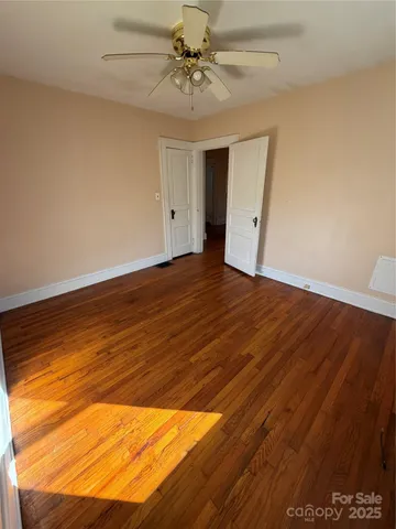 a view of an empty room with window and wooden floor