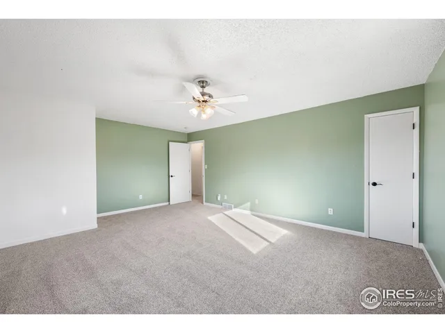 a view of an empty room with a chandelier fan
