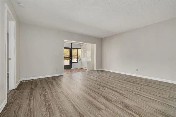 a view of an empty room with wooden floor and window