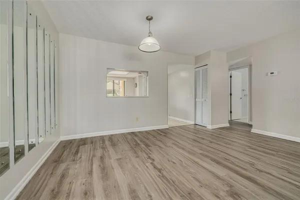 a view of empty room with wooden floor and fan