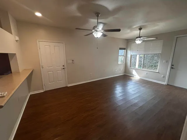 a view of an empty room with a window and wooden floor