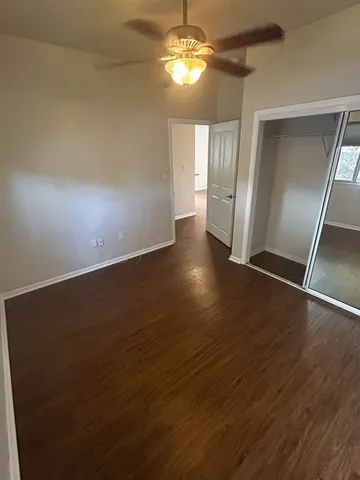 an empty room with wooden floor chandelier fan and windows