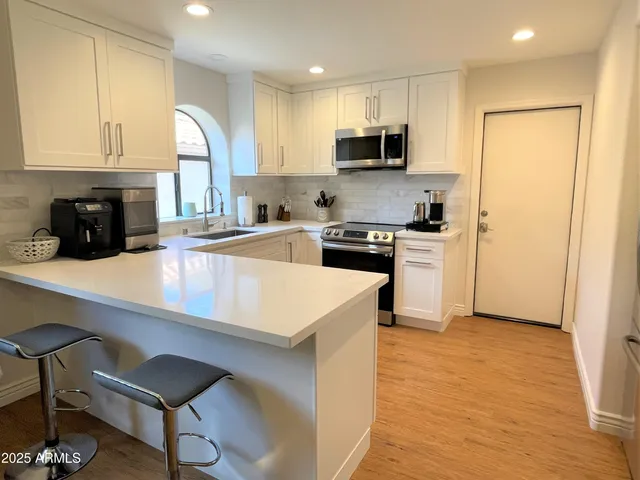 a kitchen with stainless steel appliances a stove a sink a microwave a refrigerator and cabinets