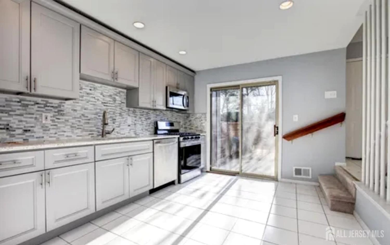 99 Kelly Drive Edison, NJ 08820 - Photo 27 of 29 a kitchen with white cabinets a sink stove and refrigerator
