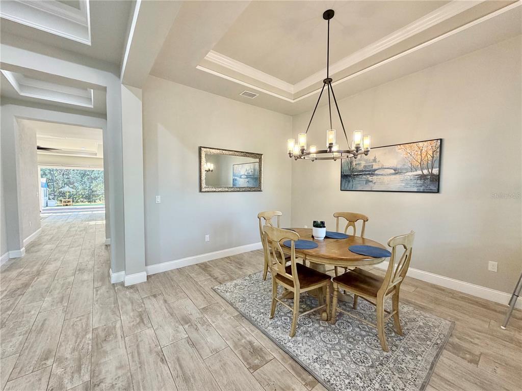 11931 Southwest 32nd Lane Gainesville, FL 32608 - Photo 3 of 78 a dining room with wooden floor a chandelier a wooden table and chairs