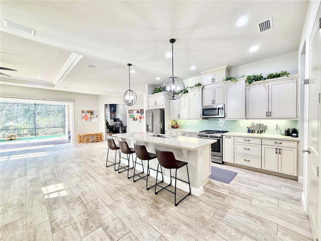 11931 Southwest 32nd Lane Gainesville, FL 32608 - Photo 5 of 78 a large kitchen with kitchen island a island a sink a stove a dining table and chairs