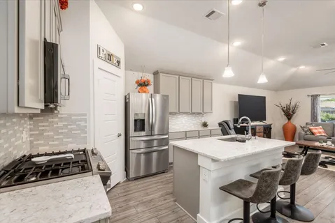 a kitchen with a refrigerator a stove a sink dishwasher with a dining table and chairs