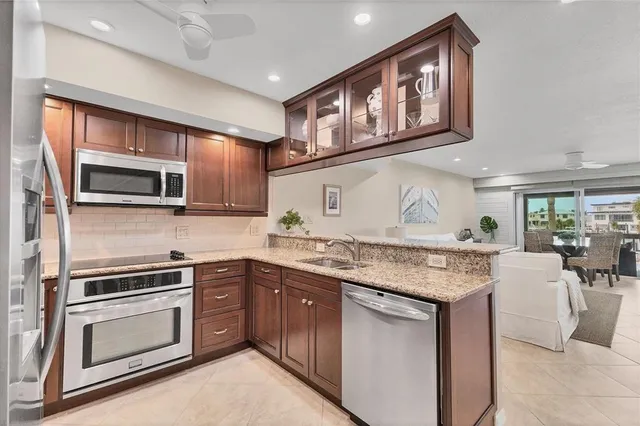 a kitchen with stainless steel appliances granite countertop a refrigerator a sink a stove a microwave and island