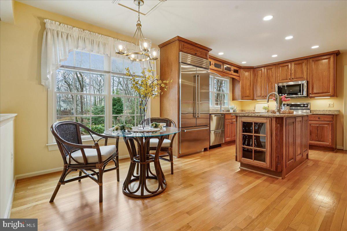 15510 Ridgecrest Drive Dumfries, VA 22025 - Photo 16 of 48 a open kitchen with stainless steel appliances granite countertop a stove top oven a refrigerator a dining table and chairs with wooden floor