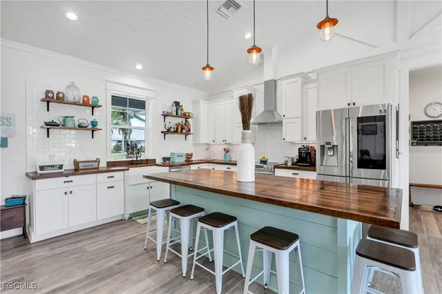 a kitchen with stainless steel appliances granite countertop a sink a stove a refrigerator cabinets and chairs